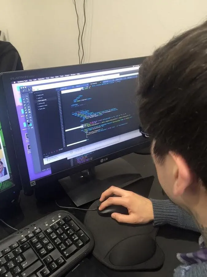 Integrante del equipo programando frente a un monitor en la oficina